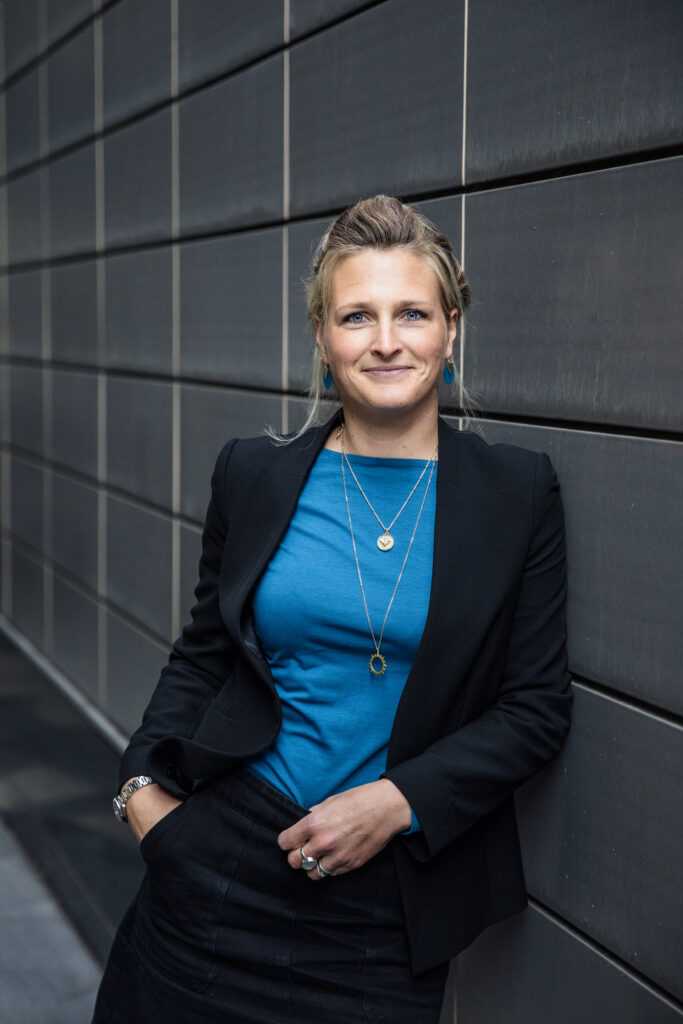 Happy business woman leaning against wall